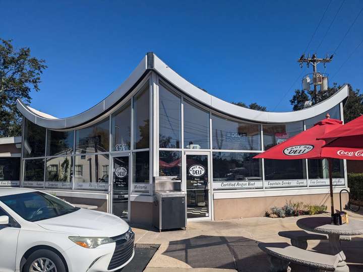 A deli with a large glass windows and a swooping roof