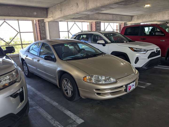 A dull gold full size sedan inside a parking garage