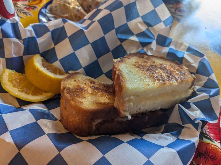 A grilled cheese served on wax paper with a slice of lemon