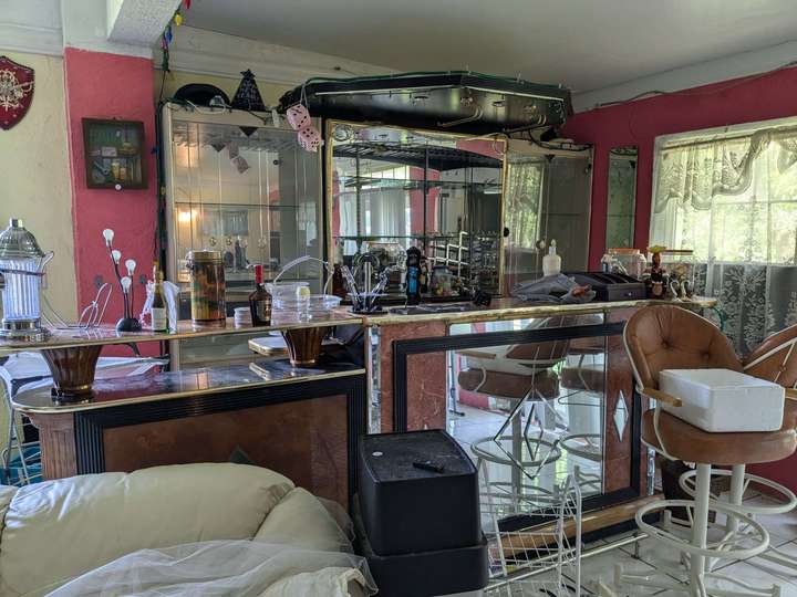 A mirror covered home bar, strewn with misc items