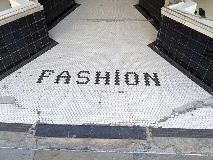 A cracked plat of hexagonal tiles. FASHION is crudely spelled