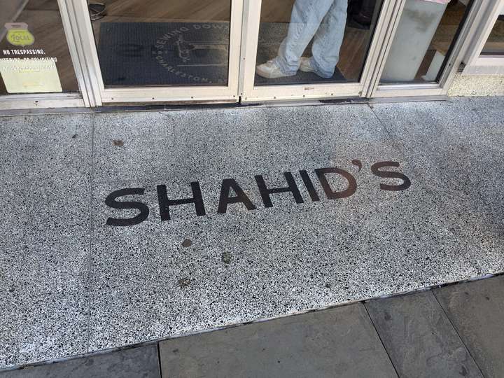 A simple design of SHAHID'S in black, block letters against a heavily speckled white background