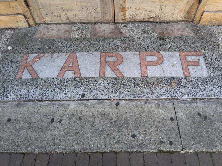 sharp, light red letters spell KARPF against a white background