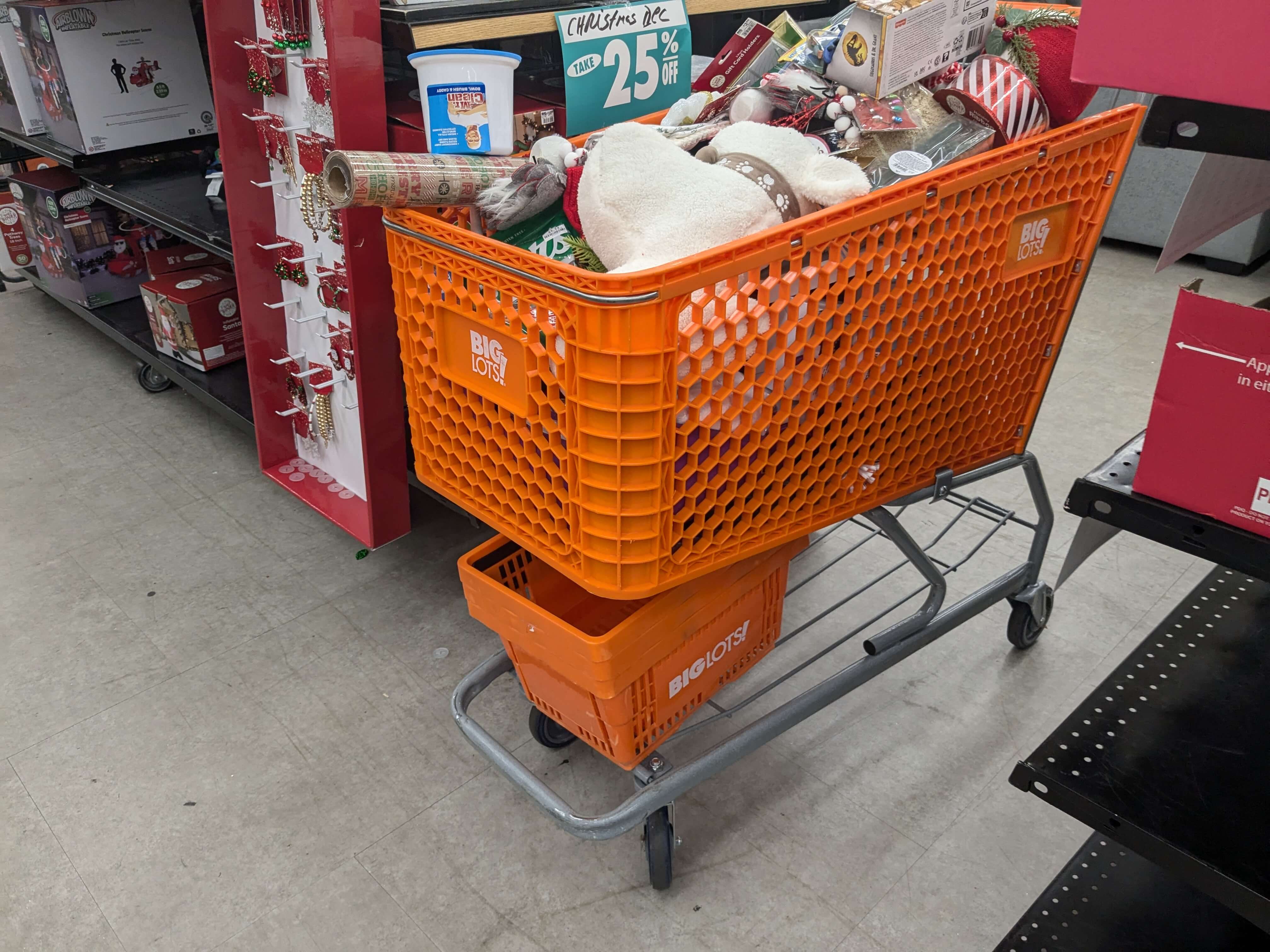 An orange shopping cart full of miscellaneous items with an orange hand basket on the bottom rack