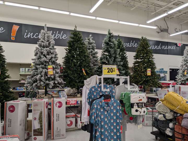 A display of Christmas trees behind a rack of Christmas pajamas