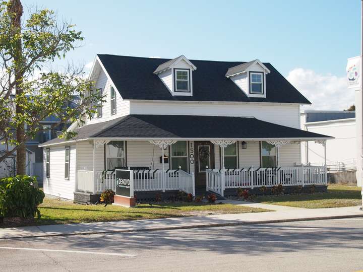 a 3/4 shot of a black and white painted two story house with a front porch