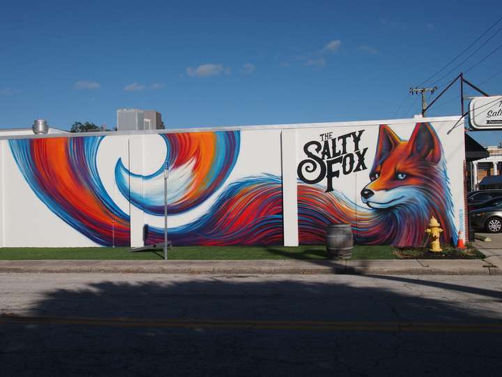 A hyper-realistic mural of a fox with a long, swirling tail