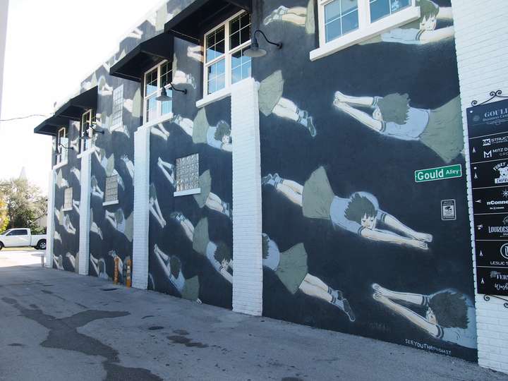 A mural featuring a repeated pattern of a girl in a diagonal, diving position on a black background