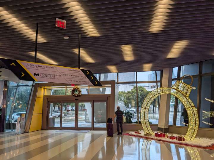 A glass wall and set of doors, behind a modernist sculpture and a wayfinding sign