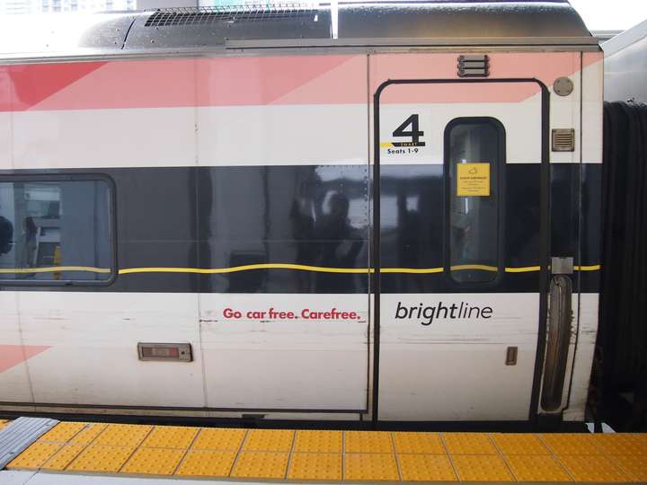 the end of a white, black, and light red train car. the slogan go car free, carefree is written on the end near the door