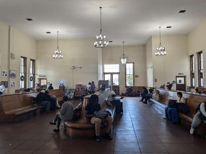 The interior of a large passenger station, showing rows of curved wooden benches