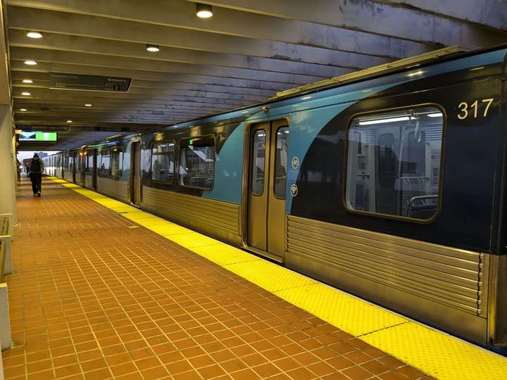 A 3/4 side view of a stainless steel and wrap metro train